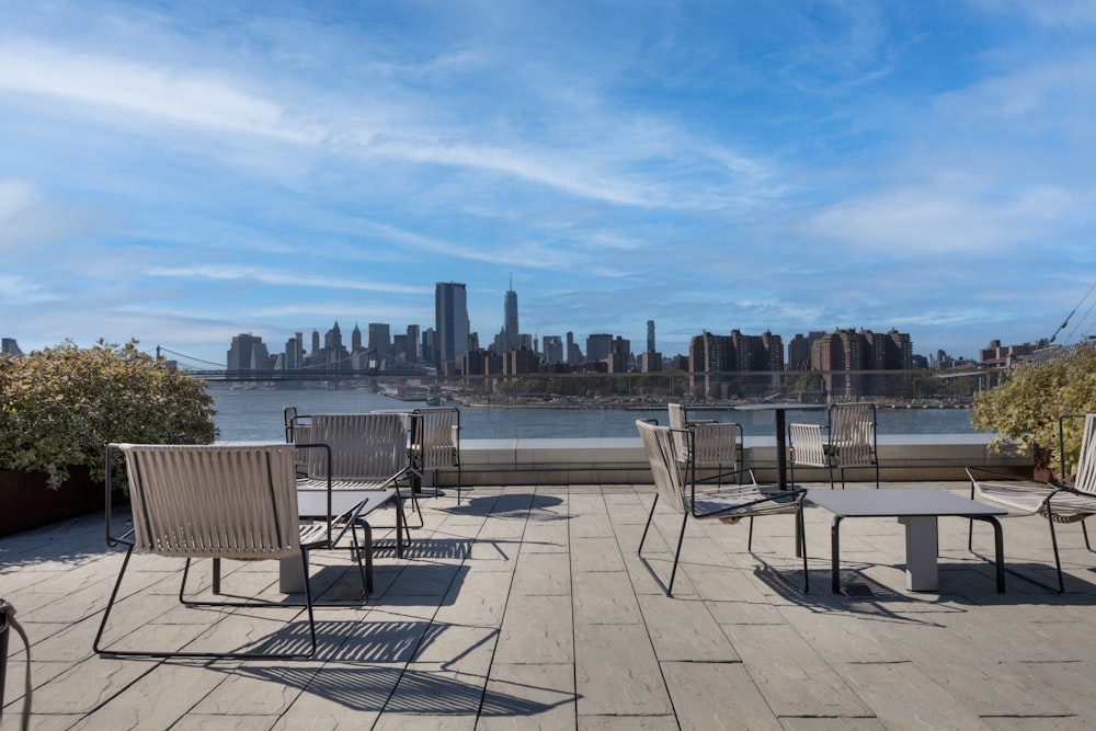 Eine Gruppe von Tischen und Stühlen auf einer Terrasse mit Blick auf eine Stadt