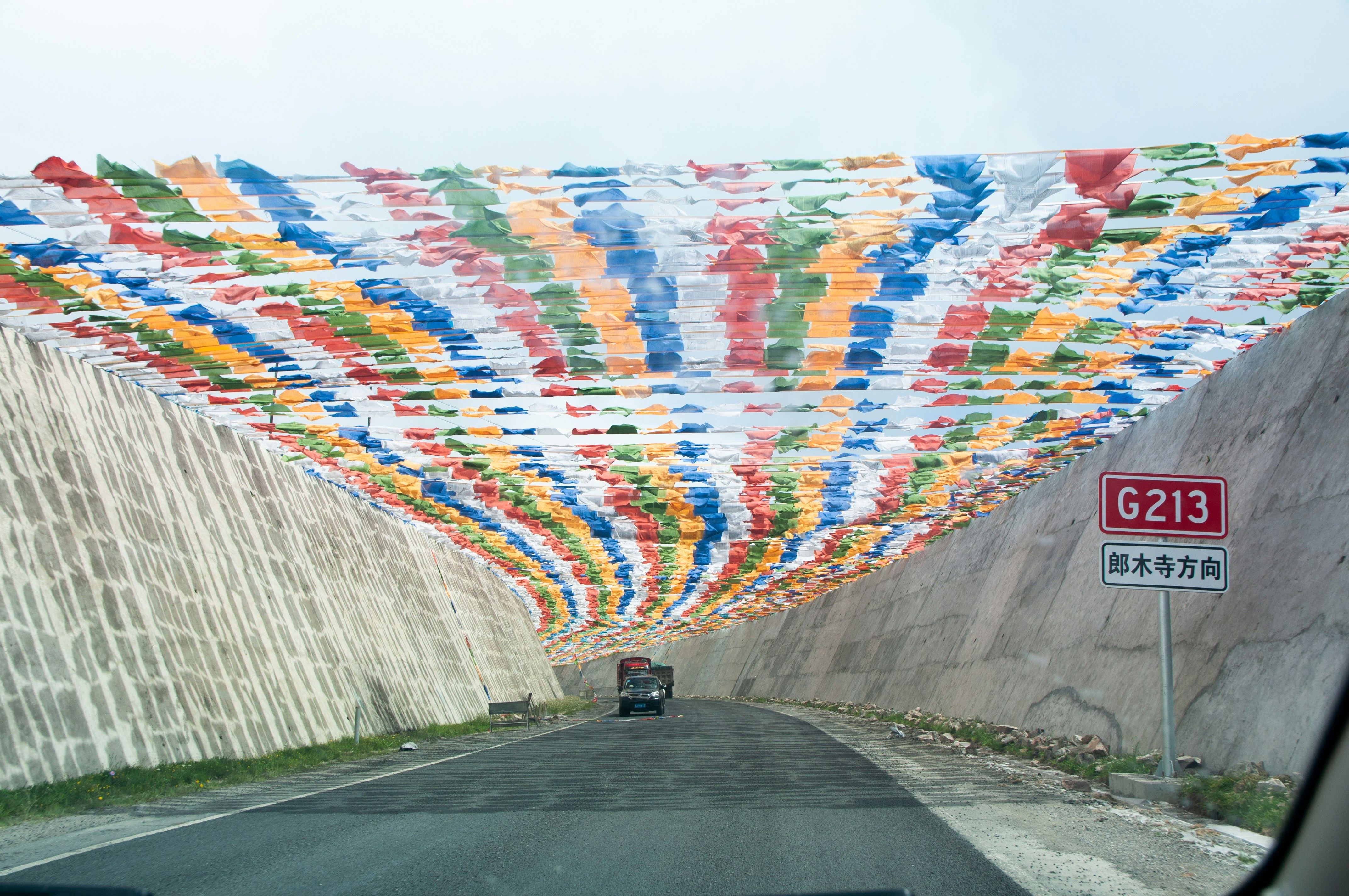 um carro dirigindo em uma estrada com uma parede de tecido colorido