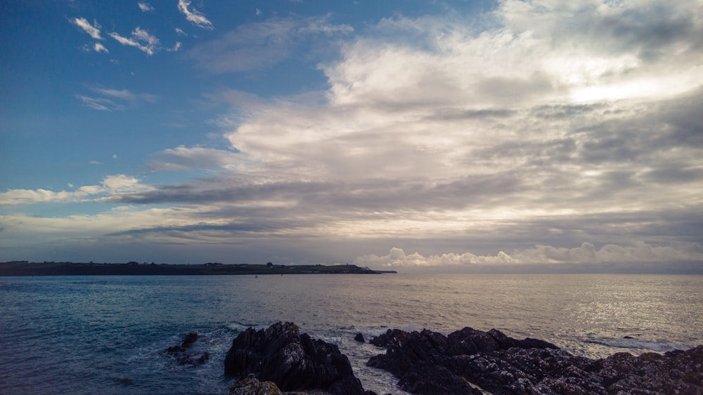 a body of water with rocks and land in the distance