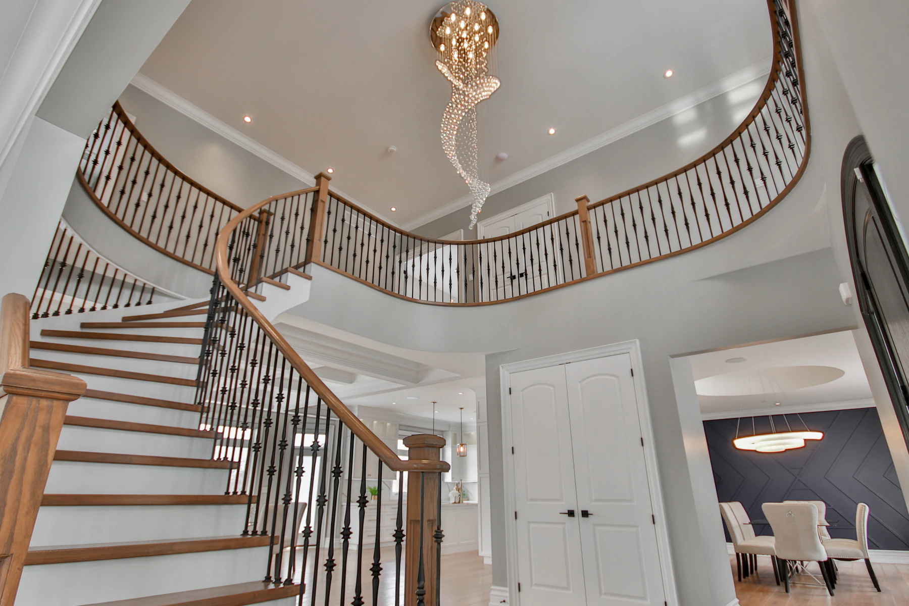 Two-story stairwell with chandelier viewed from the lower floor for checking hanging height, landing sightlines, and vertical scale