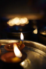 A serene portrait of Gattupalli Manisarma surrounded by sacred fire and traditional temple lamps glowing softly.