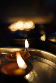 Softly lit camphor flames flickering gently on a decorated silver plate during a puja.
