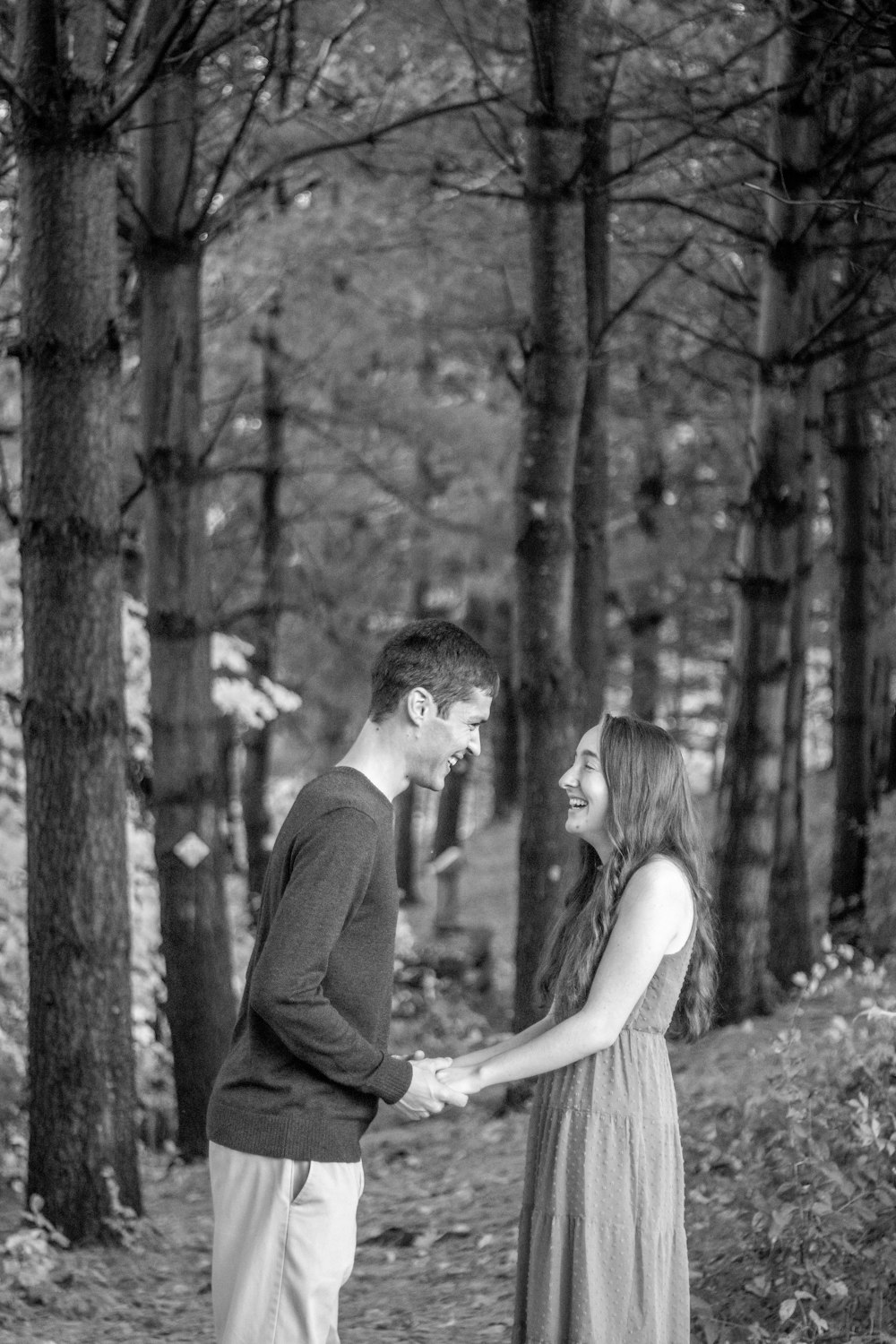 a man and woman holding hands in the woods