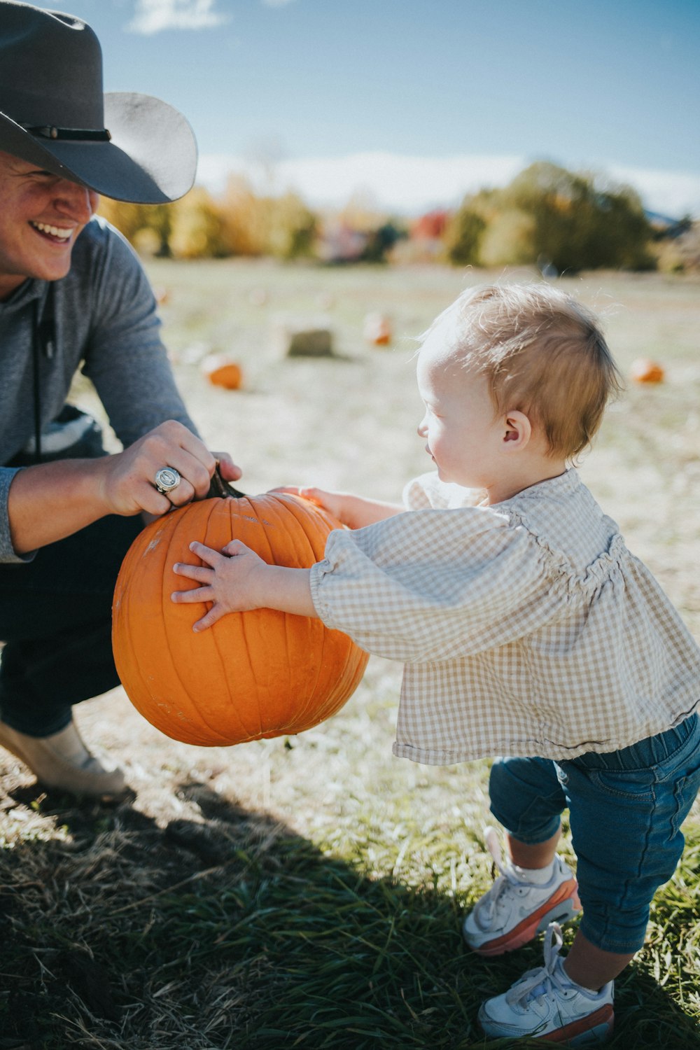 a person and a child holding a pumpkin