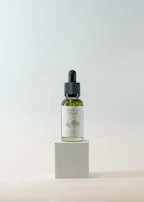 Luxurious product display with biotin and hair oil bottles glowing subtly against dark green backdrop.