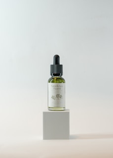 Close-up of a delicate glass bottle of musk lush organic hair oil surrounded by fresh botanicals.