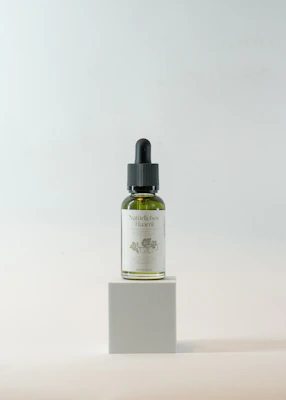 Close-up of a sleek bottle of nourishing hair oil with golden liquid inside, set against a soft beige background.