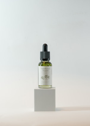 Bottle of herbal hair oil with fresh herbs around it