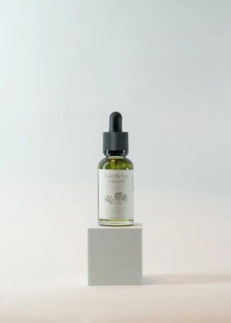 Close-up of a bottle of hair oil with fresh botanical ingredients around it.