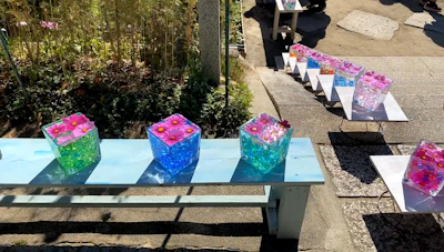 Colorful stash containers displayed outdoors on a picnic blanket under natural light.