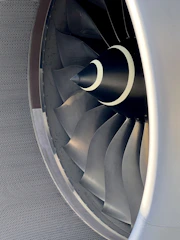 Close-up of a finely machined aerospace turbine blade reflecting light.