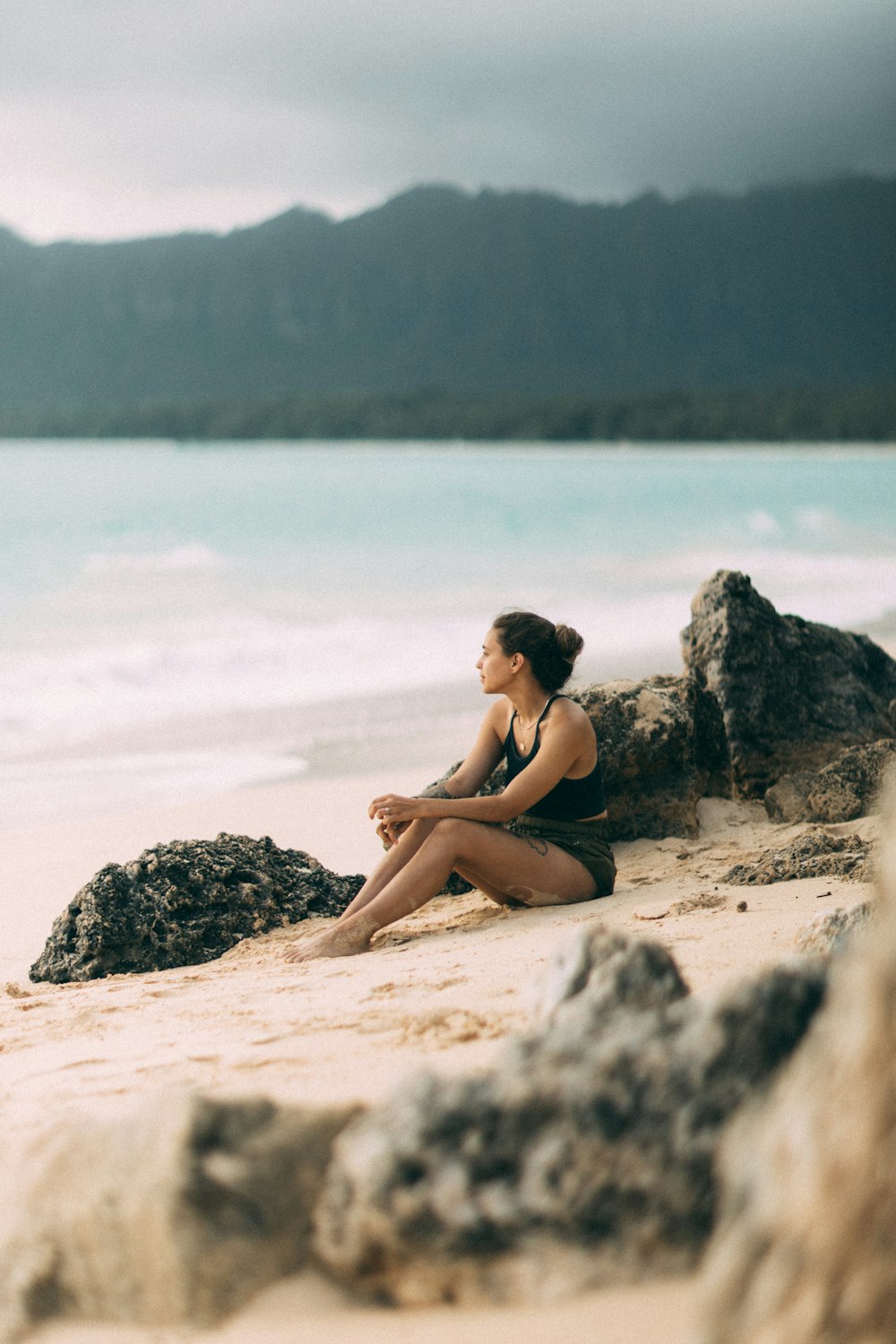 a person sitting on a rock by the water