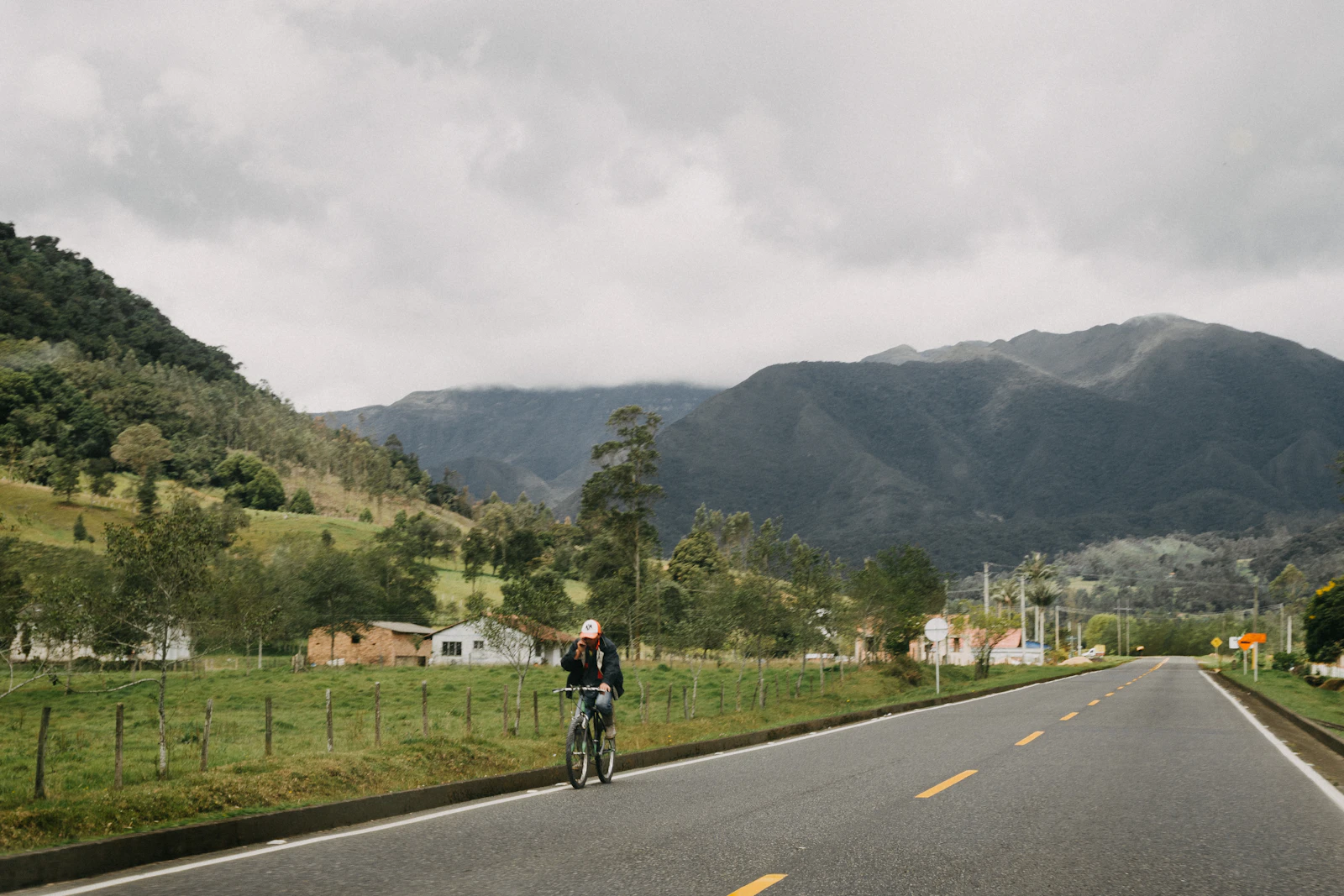 A cyclist and vehicle sharing a paved mountain road in Colombia