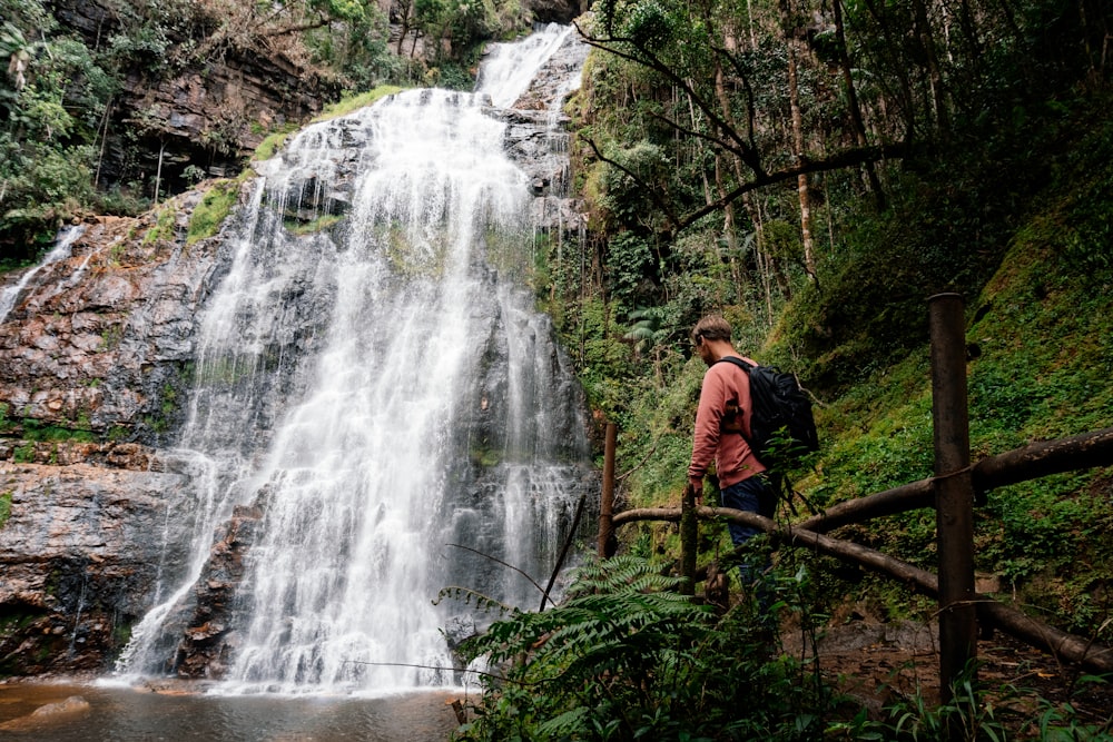 a man walking on a bridge over a waterfall