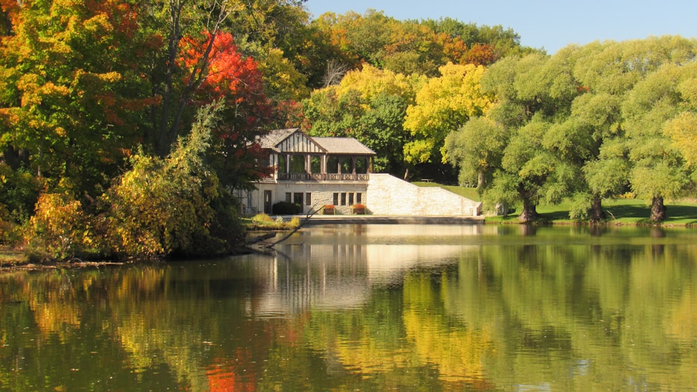 a house on a hill by a lake with trees around it