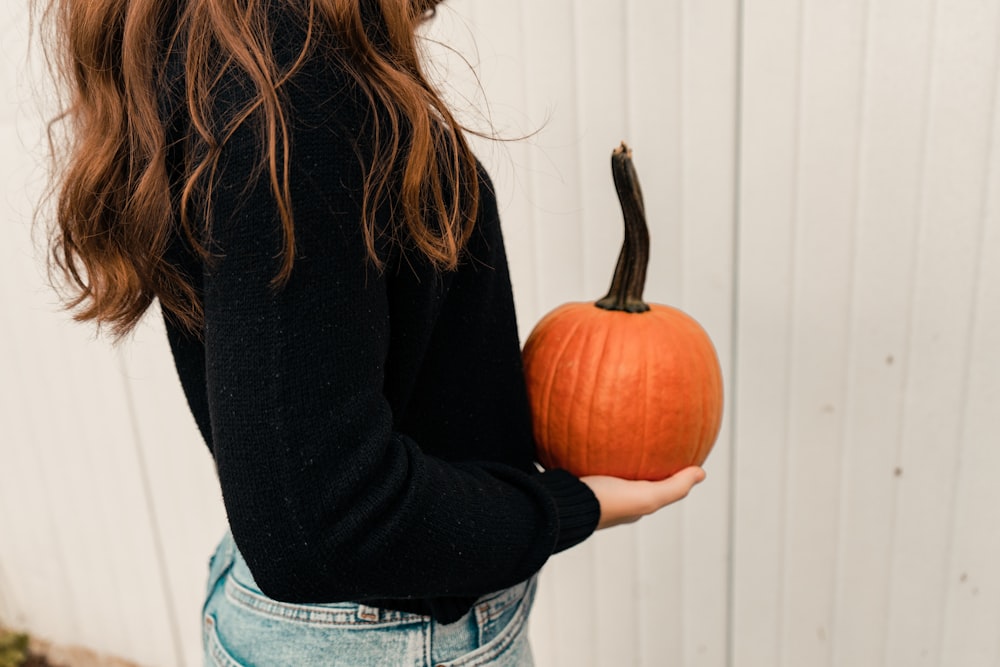 a woman holding a pumpkin