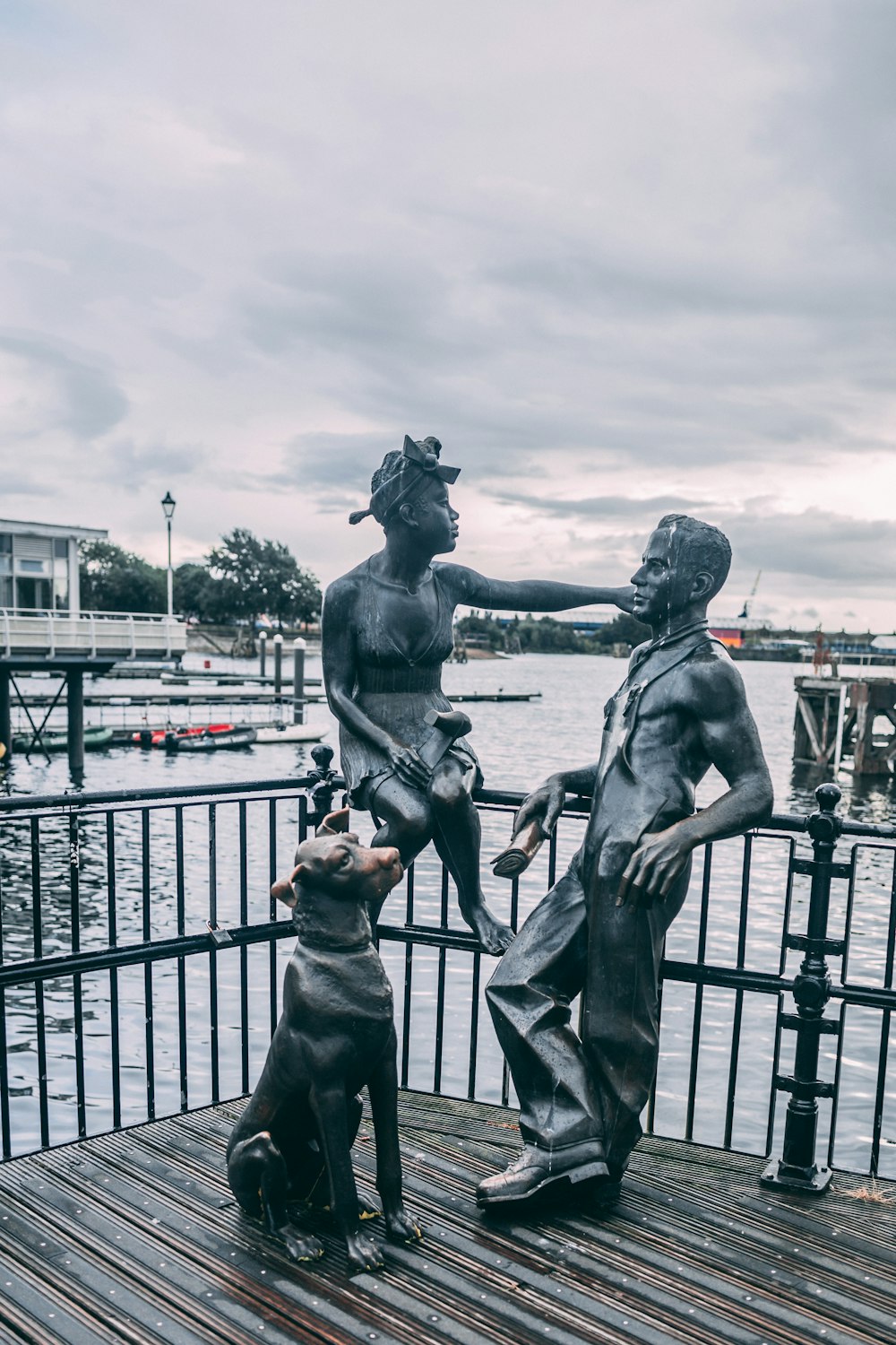 una estatua de una persona y un perro junto a un cuerpo de agua