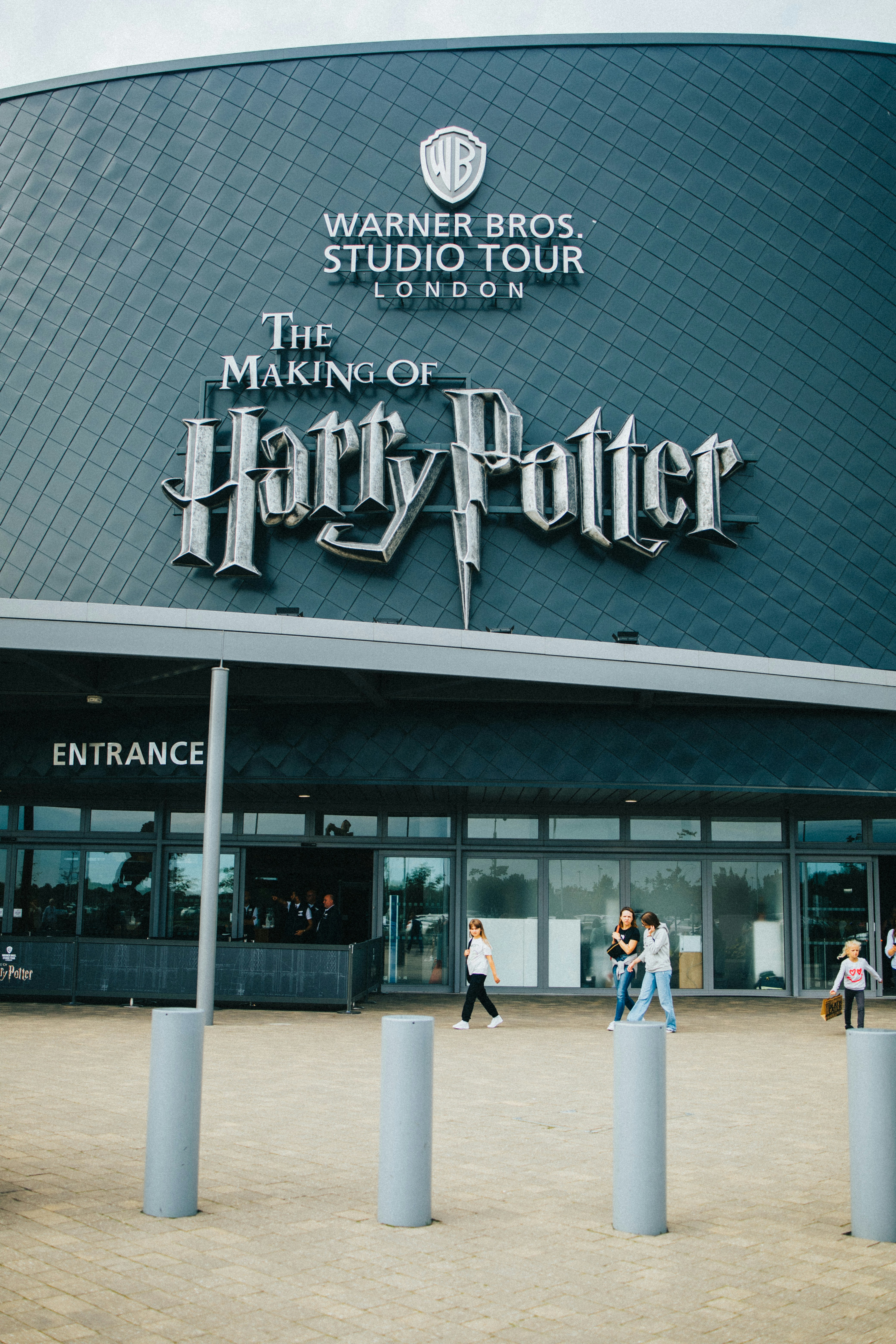 Facade of Warner Bros Studio Tour London with 'The Making of Harry Potter' sign and entrance area with people walking