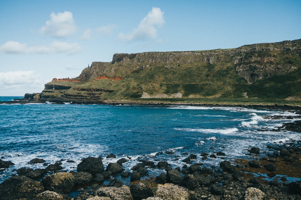 a rocky beach with a hill in the background