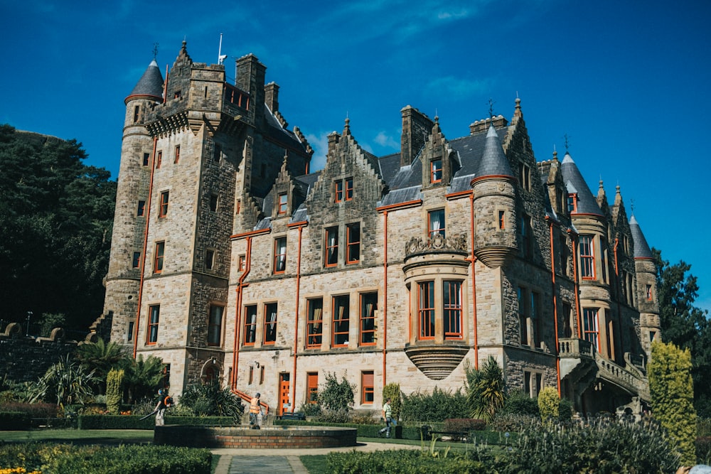 a large building with a garden in front of it with Belfast Castle in the background