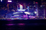 A striking black and purple cityscape at night with glowing neon signs.