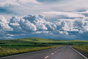 a road with grass and clouds above
