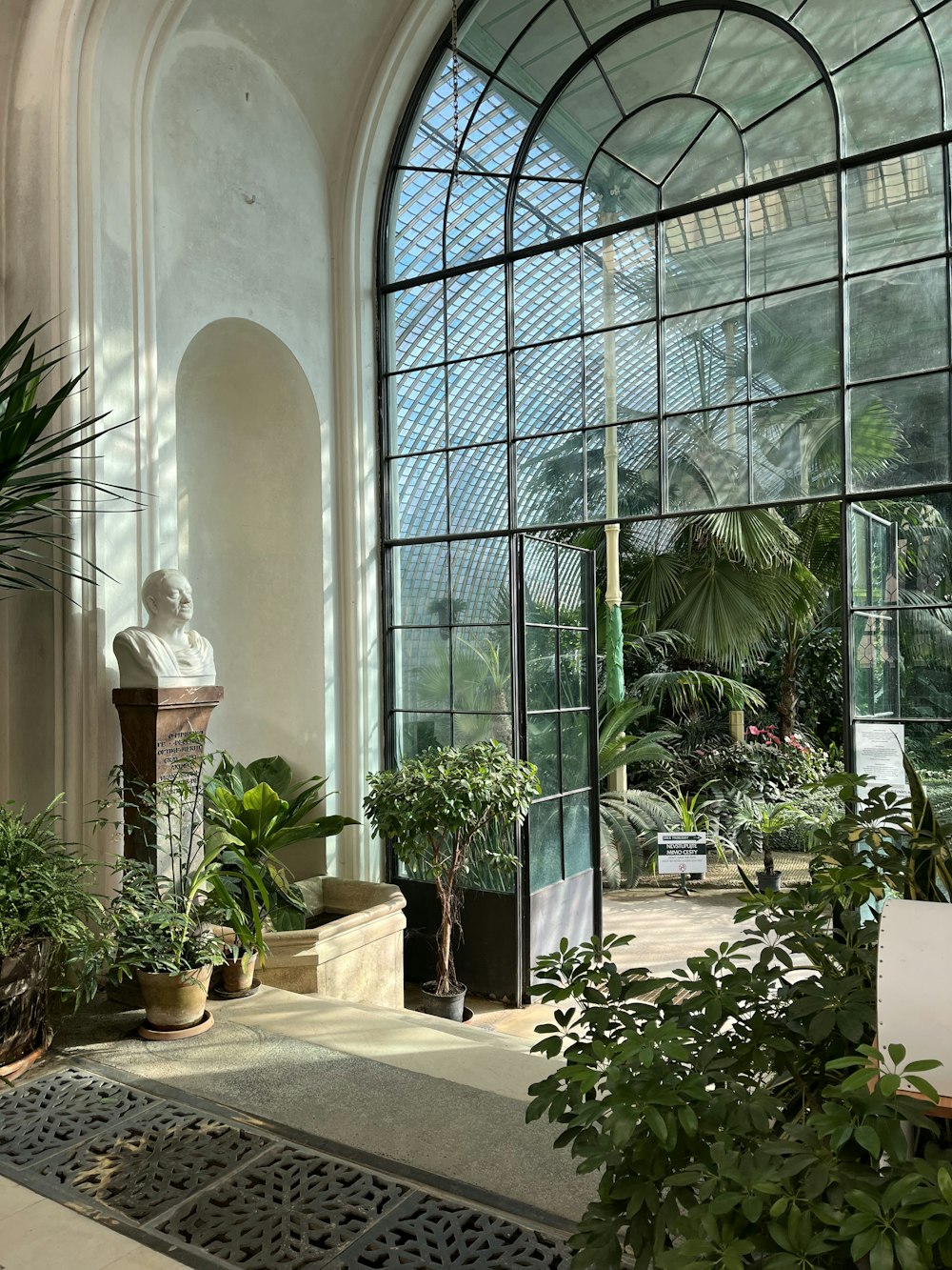 a glass walled building with plants and a statue in the middle