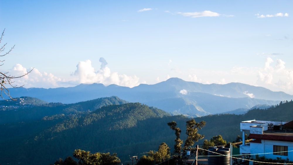 a building on a hill with trees and mountains in the background