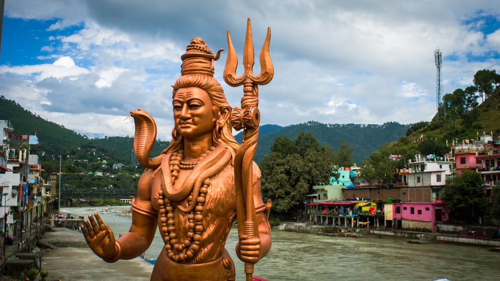 a statue of a person holding a torch by a body of water