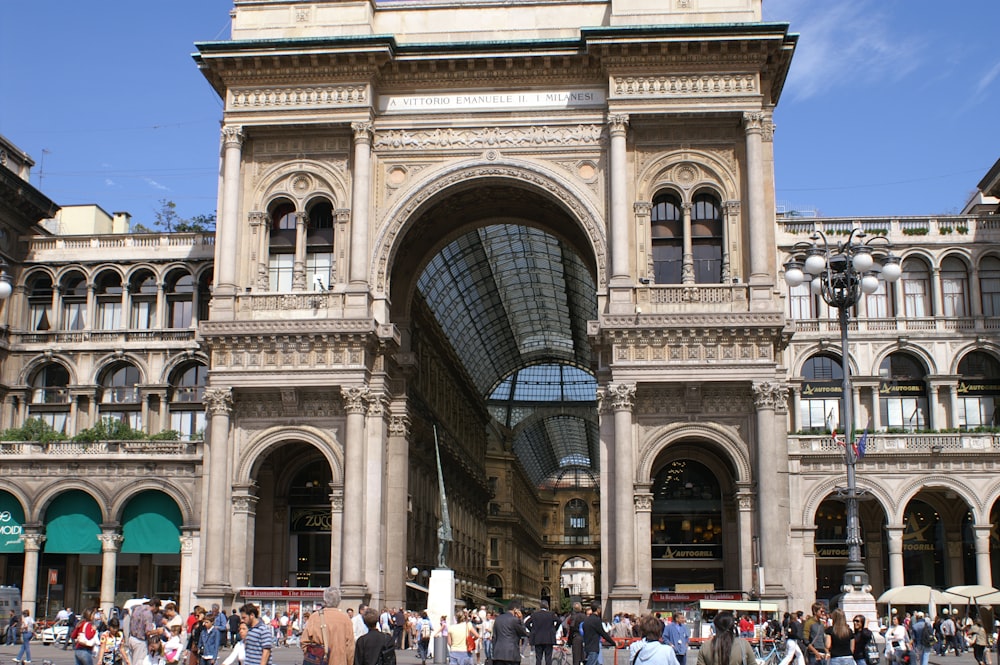 a large stone building with many arches with Galleria Vittorio Emanuele II in the background