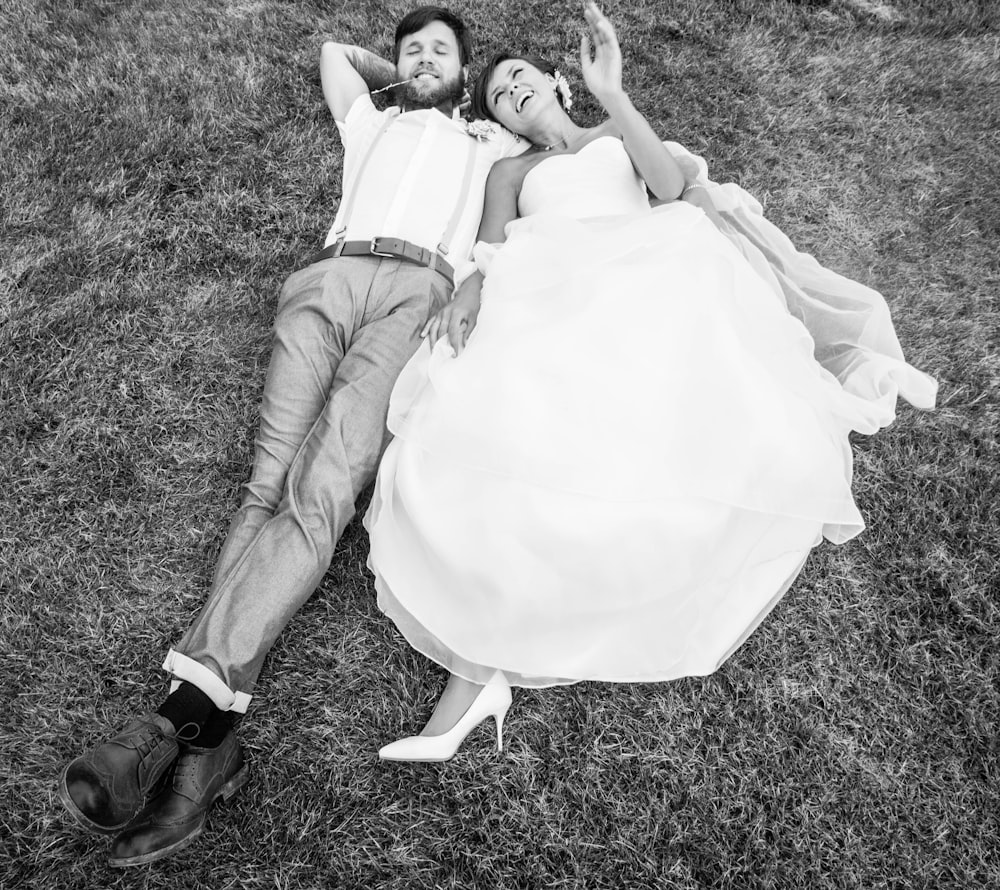 a man and woman in wedding attire lying on the grass