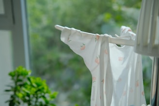 Flowy a-line nightie with subtle floral prints hanging near a sunlit window.