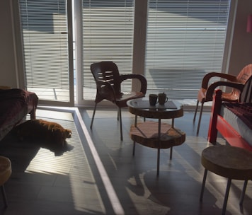 A cozy living room being tidied up with sunlight streaming through the window.