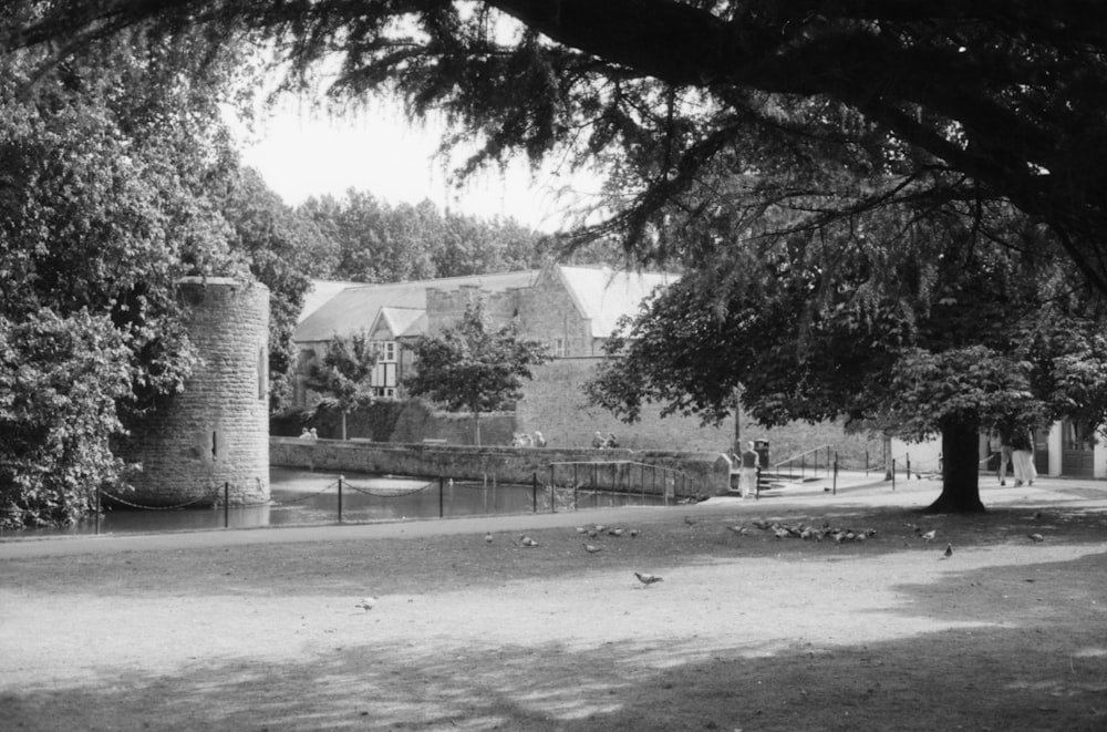 a black and white photo of a house with trees and a fence