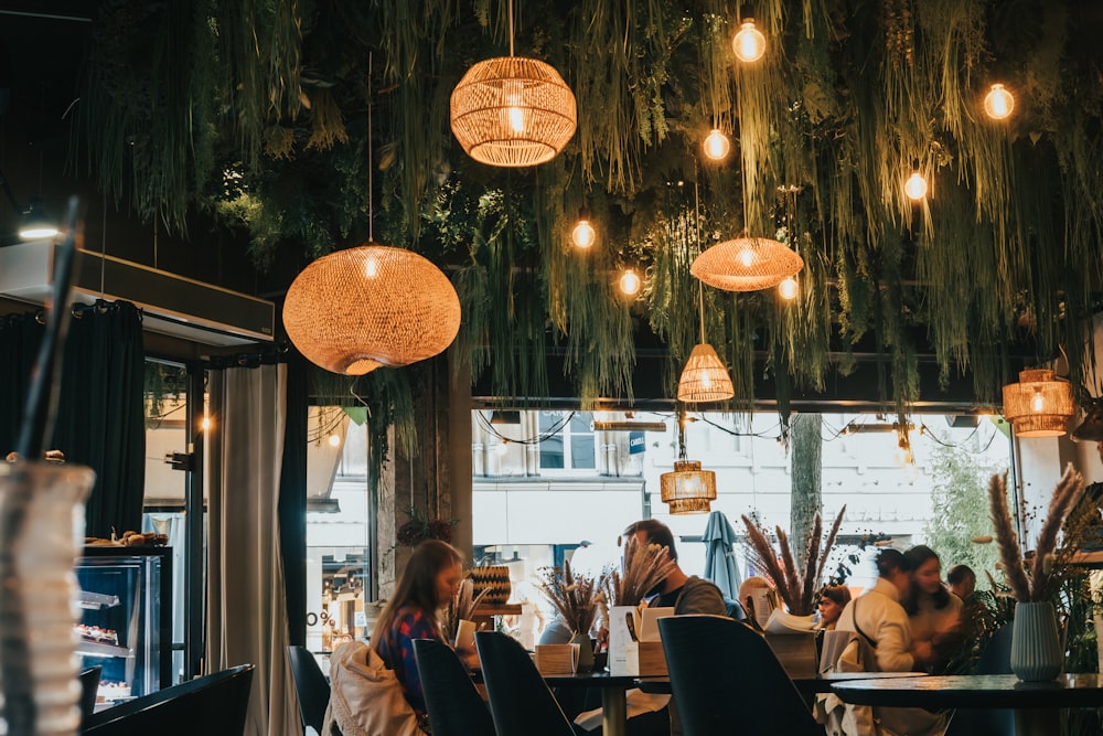 a group of people sitting at tables under lanterns