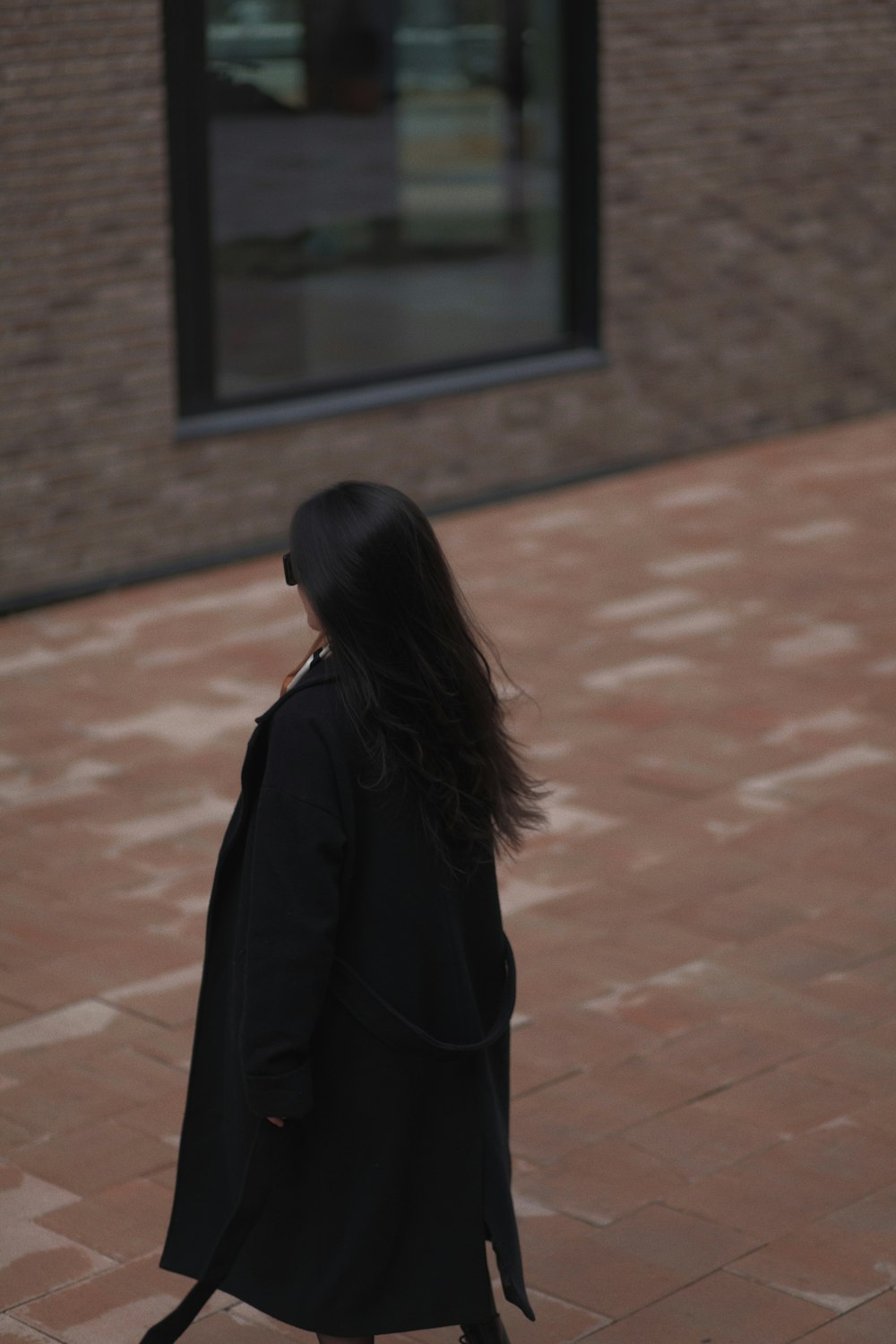 a woman walking on a brick sidewalk