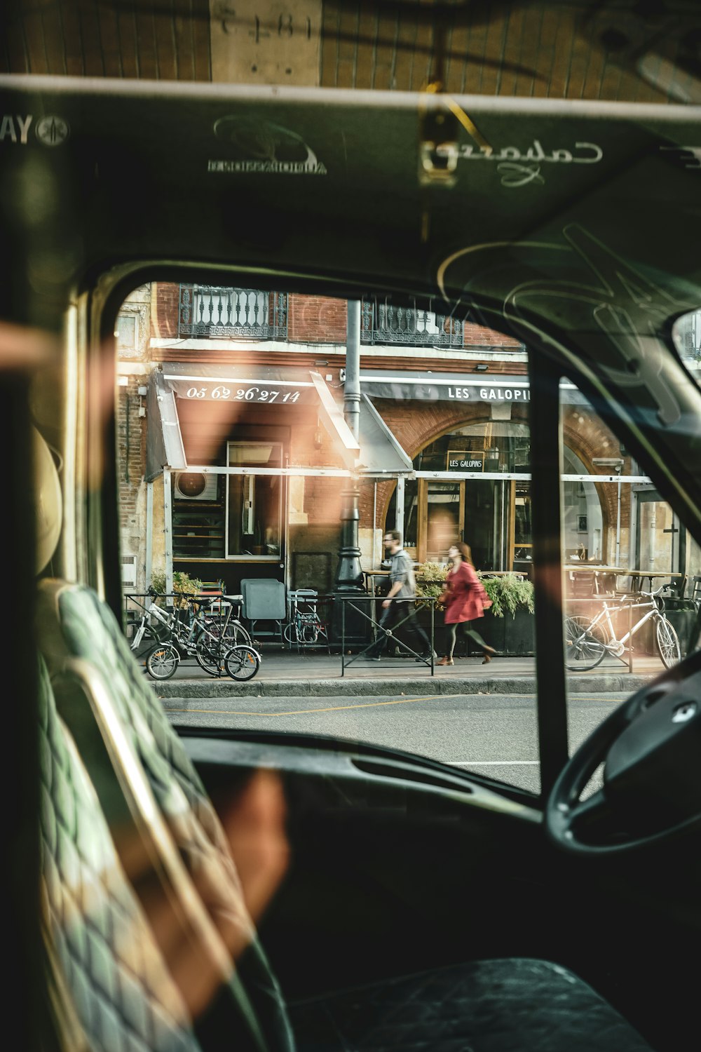 a car mirror showing a couple of people walking down a street