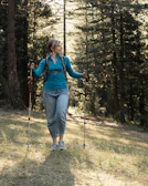 A hiker wearing a hypershell exoskeleton walking through a sunlit forest trail in the Tatra Mountains
