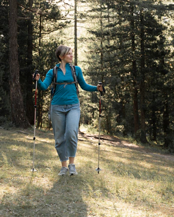 A hiker wearing a hypershell exoskeleton walking through a sunlit forest trail in the Tatra Mountains