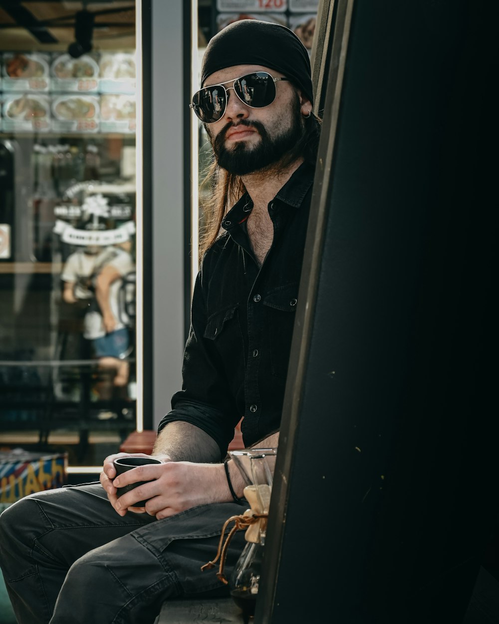 a person in a black hat and sunglasses sitting on a subway