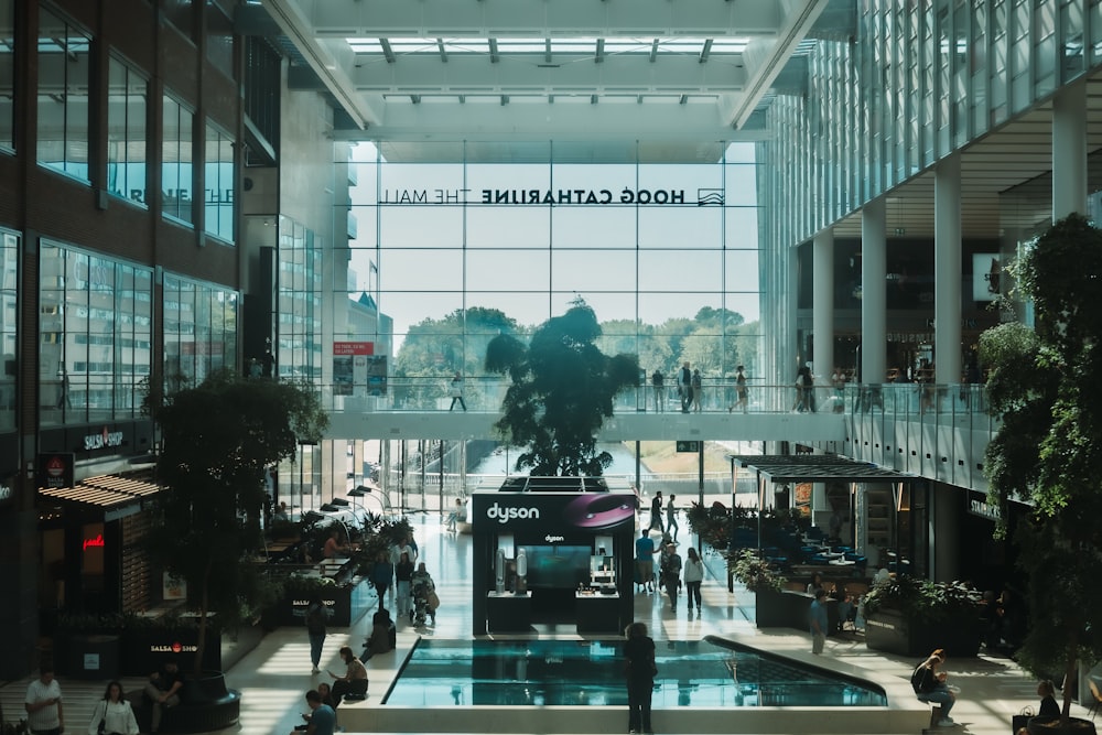 a large glass building with a bus and people walking around