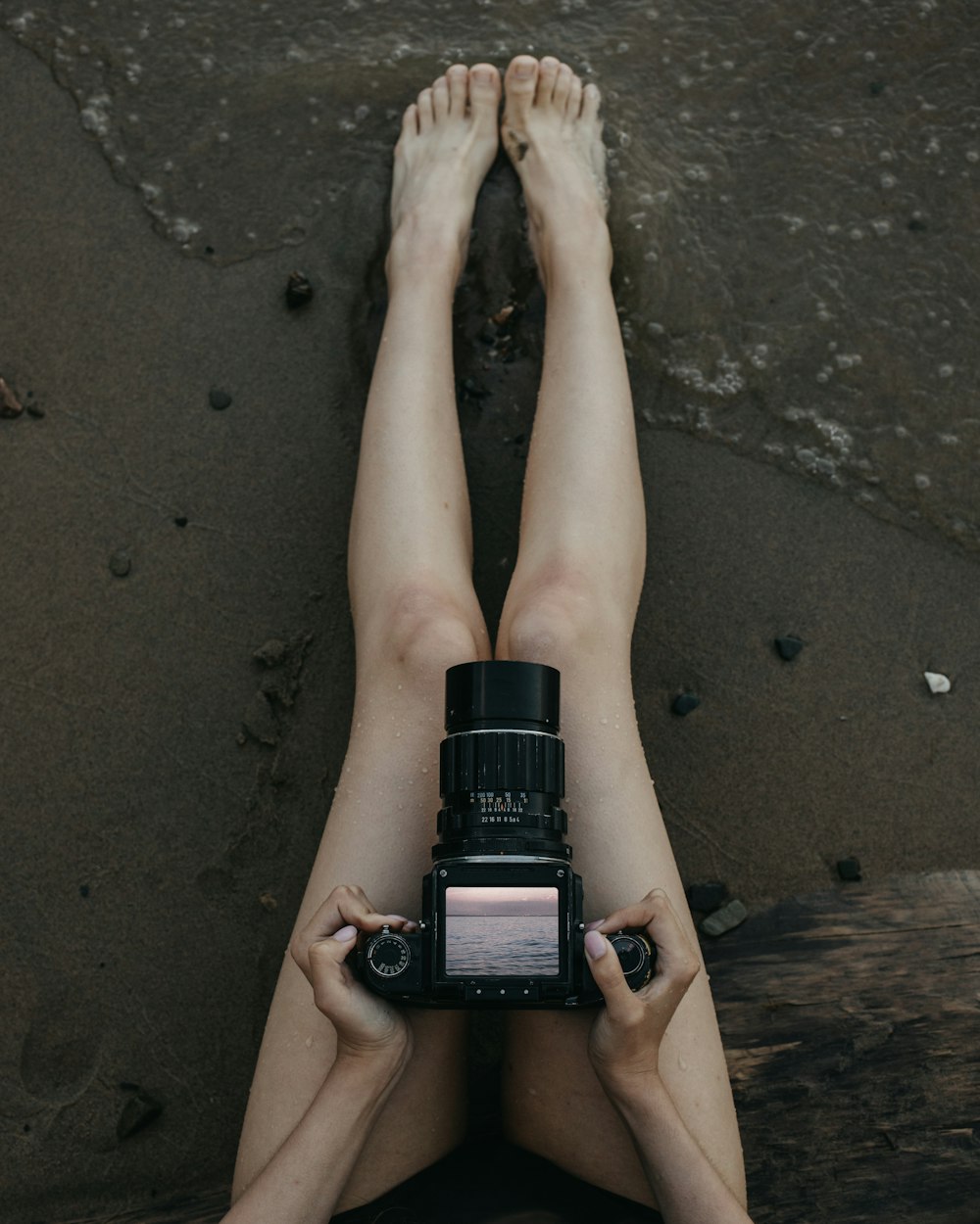 a person's feet on a beach with a watch on