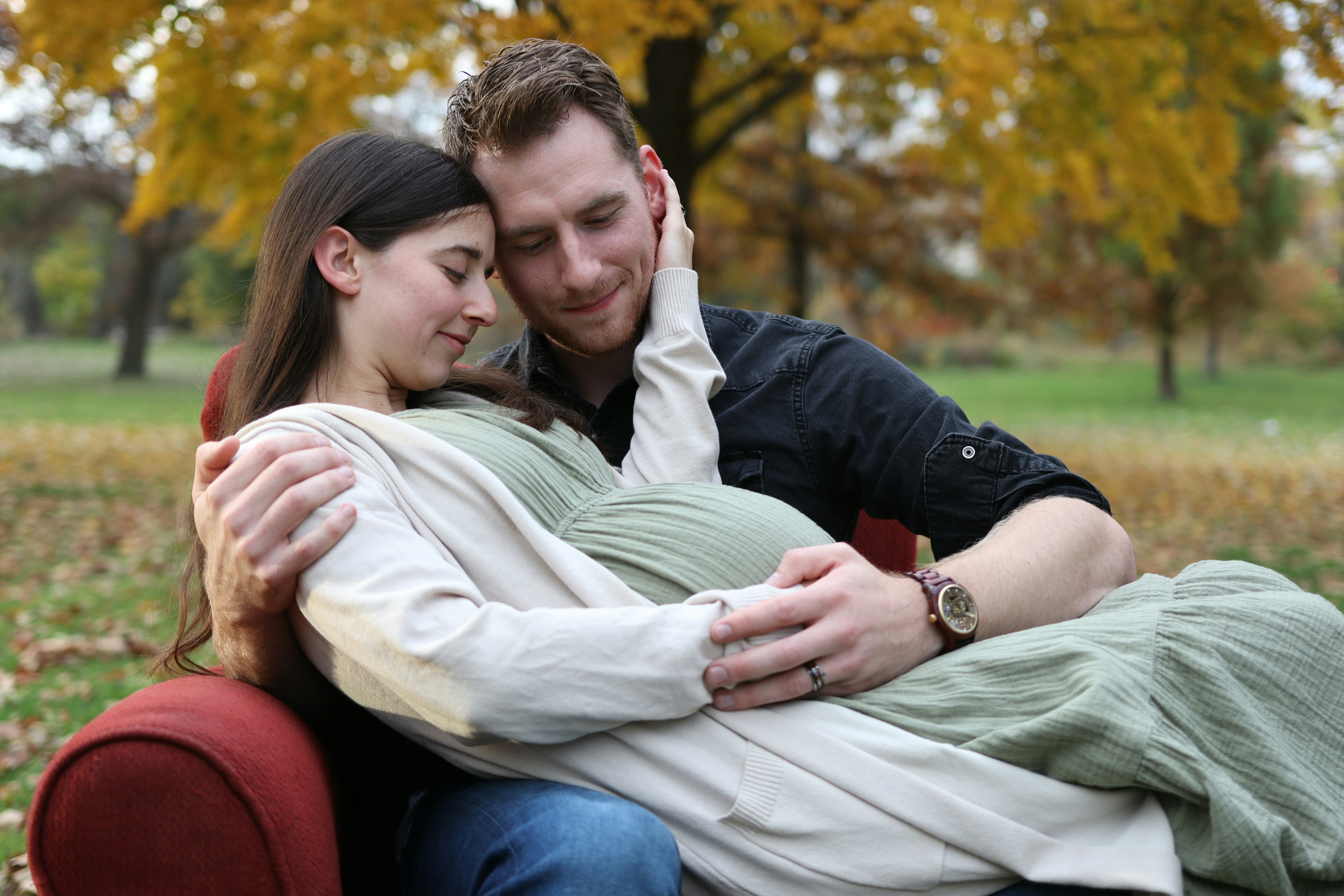 pregnant couple hugging tenderly outdoors in warm autumn light
