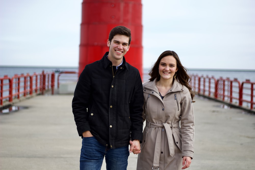 a man and woman posing for a picture in front of a red bridge