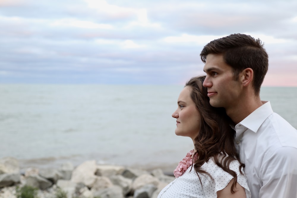 a man and woman looking at each other on a rocky beach