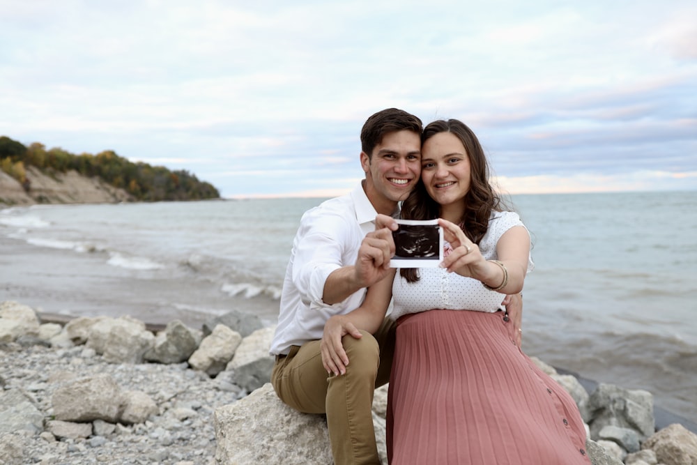 a man and woman posing for a picture on a rocky beach