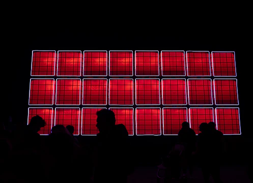 a group of people looking at a large window with red and blue lights