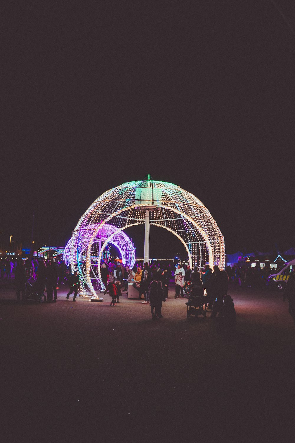 um grupo de pessoas na frente de uma roda gigante iluminada
