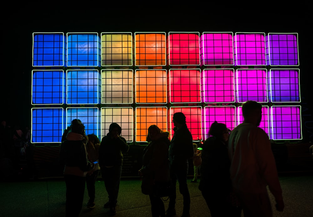 a group of people standing in front of a large window with colorful lights