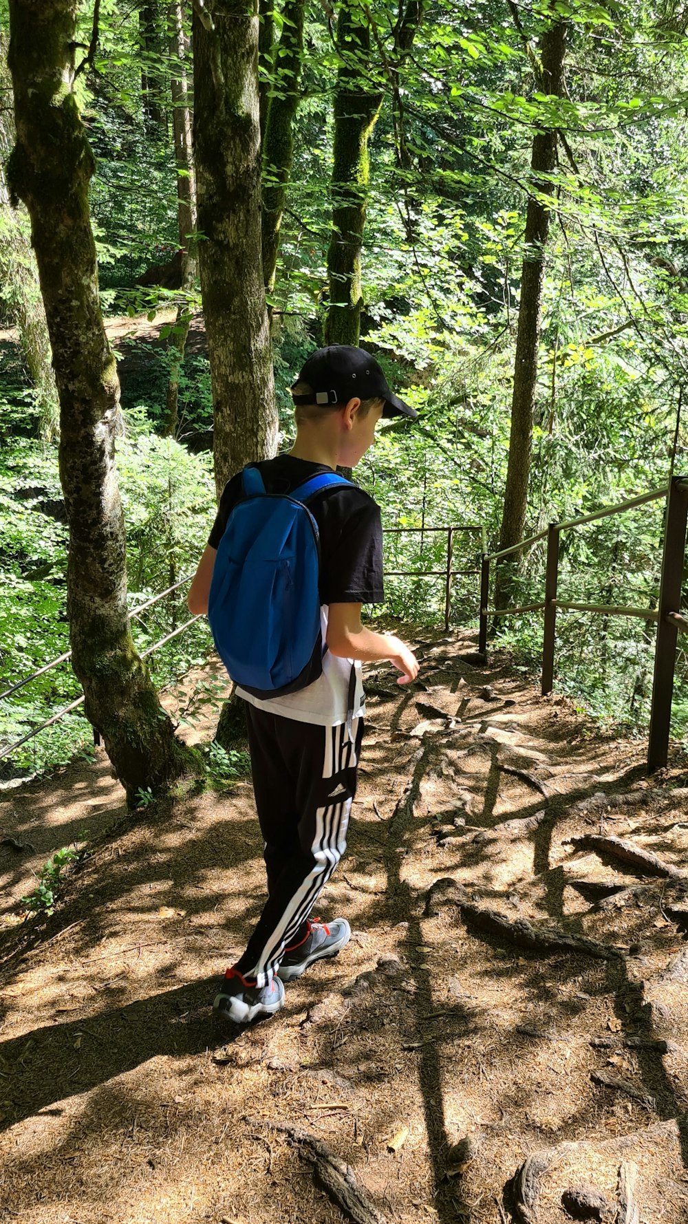 a boy wearing a backpack and standing in a wooded area